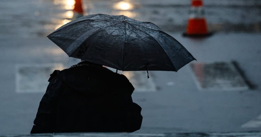 Persona con paraguas bajo la lluvia en Santiago por llegada de ciclón extratropical