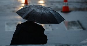 Persona con paraguas bajo la lluvia en Santiago por llegada de ciclón extratropical