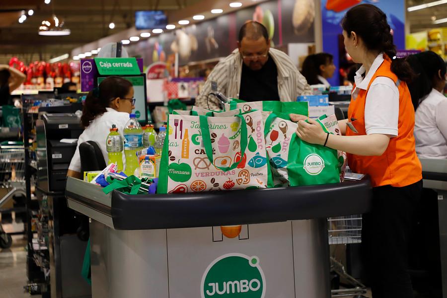 Empaquetadora asistiendo a clientes en caja de supermercado en Chile.